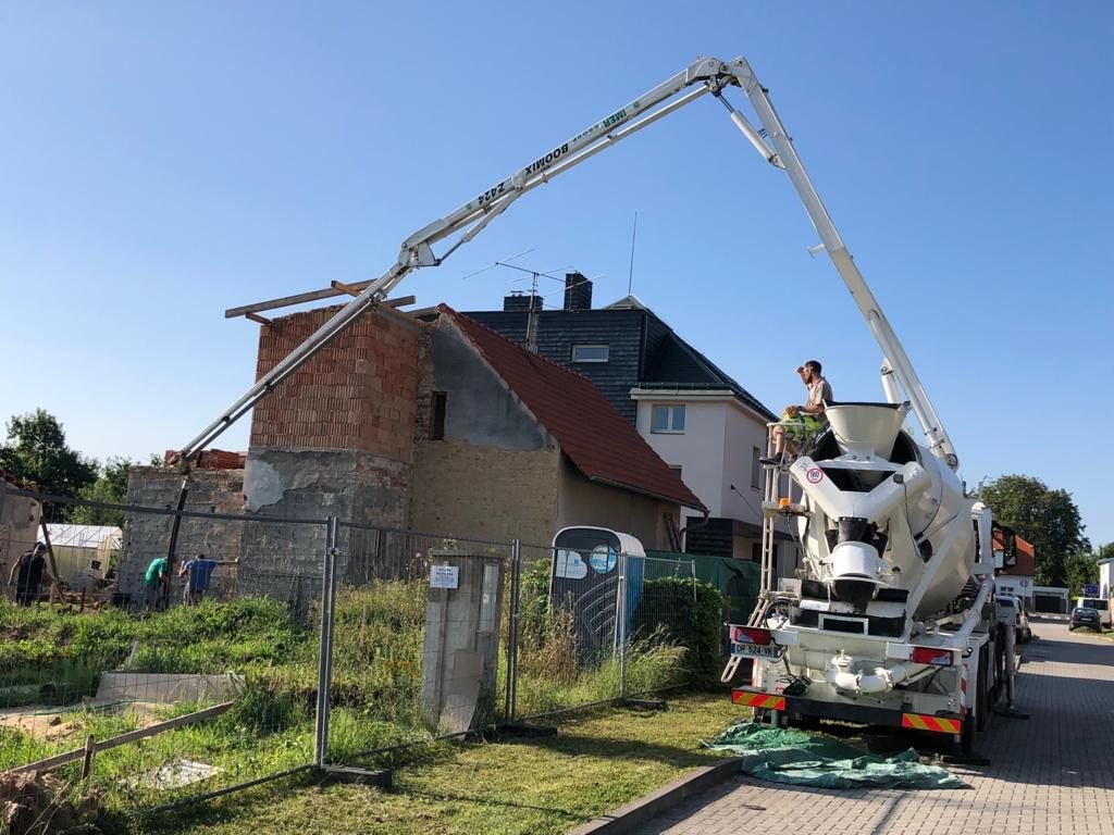 Čerpání betonu u rodinného domu — rozložené rameno čerpadla nad zahradou