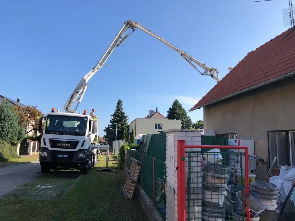 Autodomíchávač s ramenem čerpadla v úzké ulici u novostavby